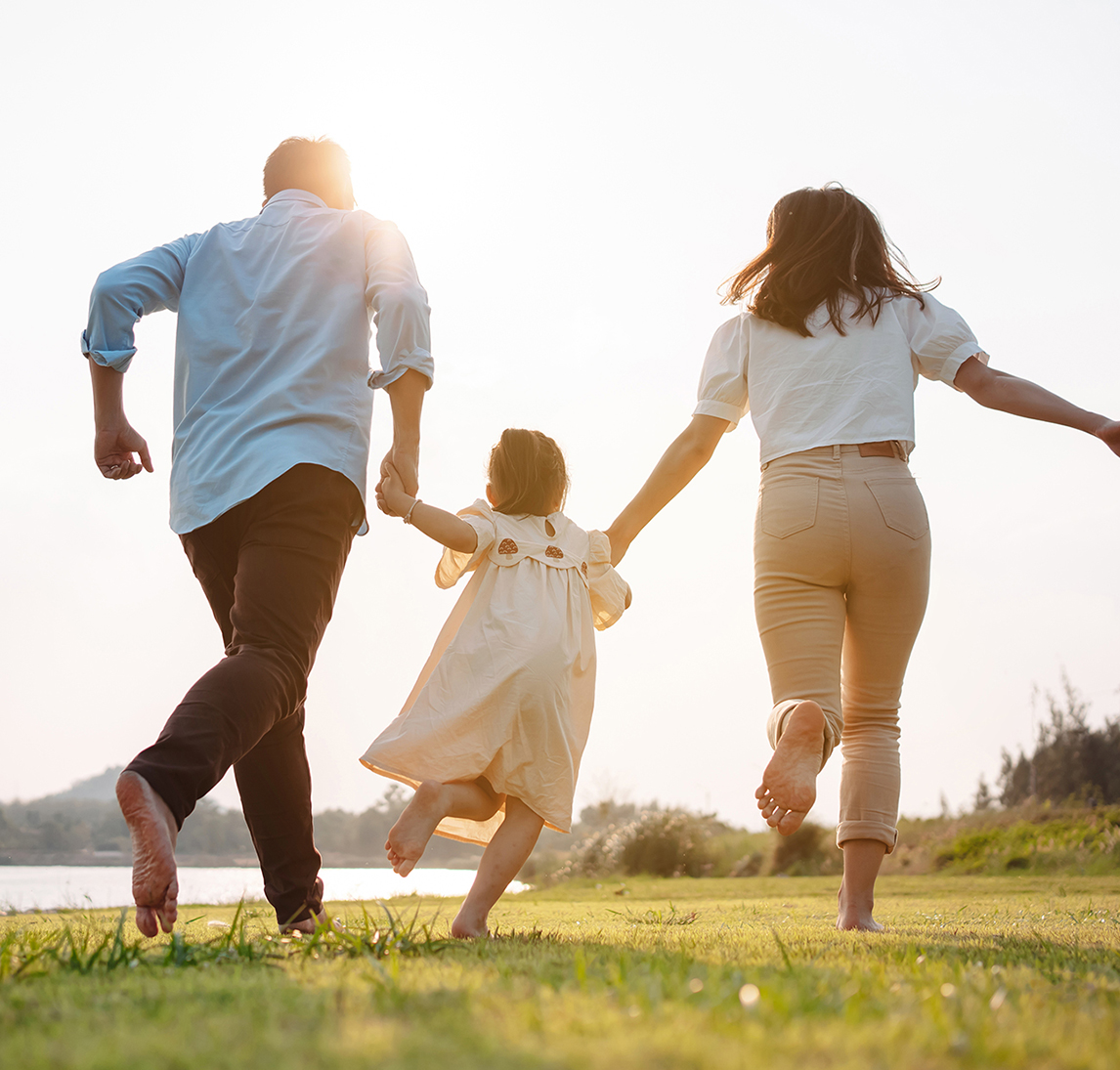 A happy family runs together while holding hands in a meadow
