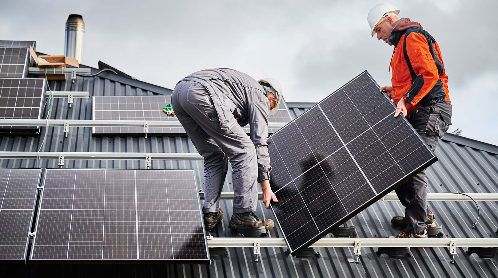 Technicians install a solar panel system on the roof of a building