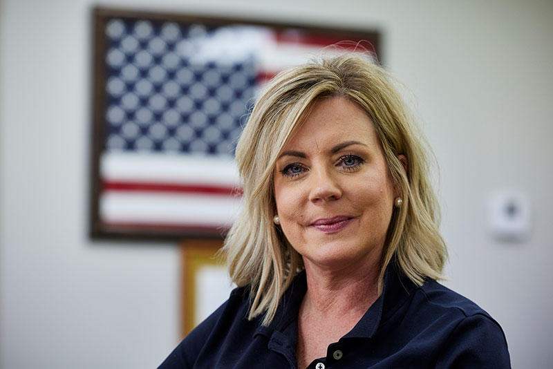 An insurance agent is seated with a smile on her face