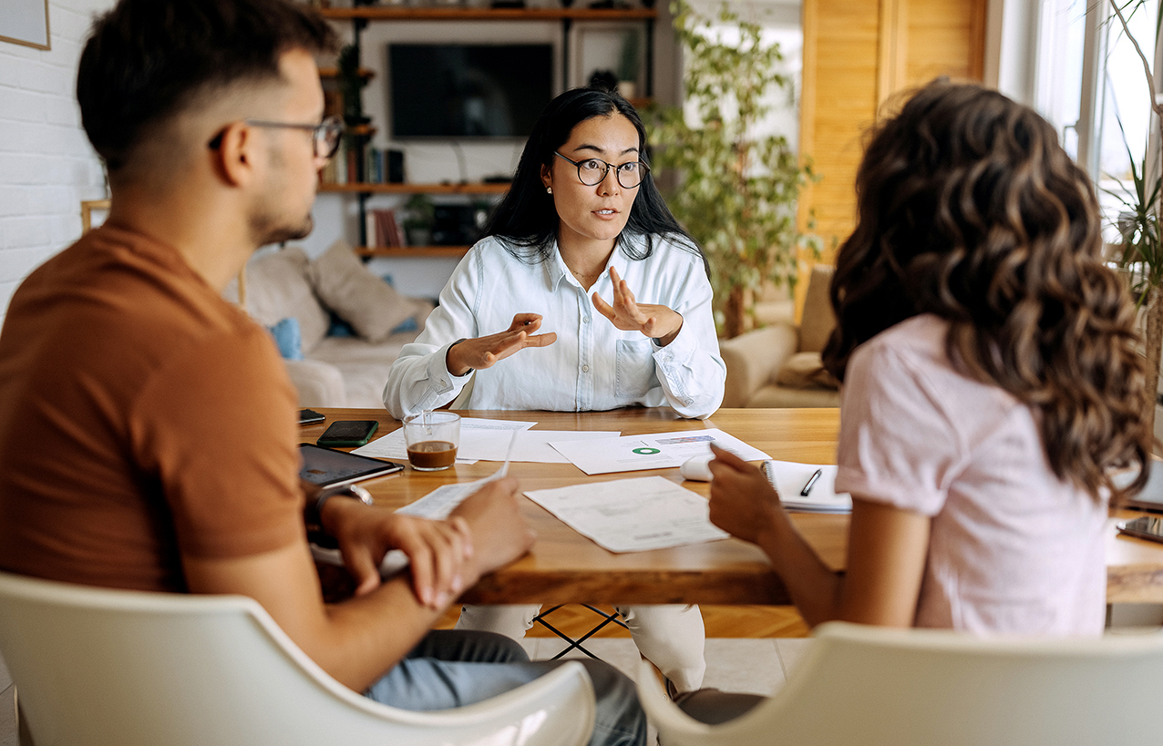 A young couple speaks with their agent at their kitchen table